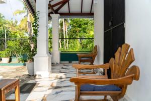 a porch with two wooden chairs and a table at JY Apartments in Negombo