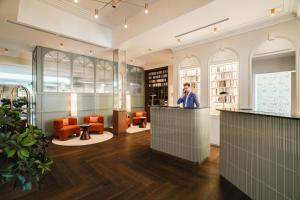 a man standing at a counter in a library with orange chairs at Hôtel Lepoussin in Cannes +79 photos