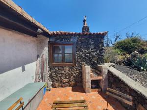 a stone house with a bench and a window at Casa Glorieta in Los Llanos de Aridane