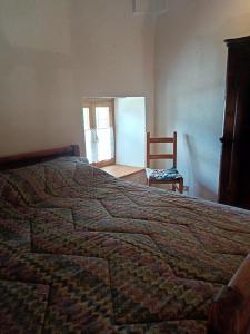 a bedroom with a bed and a chair and a window at La casetta di Marmora in Marmora