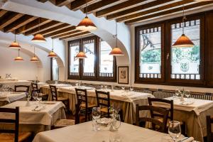 un ristorante con tavoli e sedie bianchi e finestre di Hotel Posta R.T.A. a Madonna di Campiglio