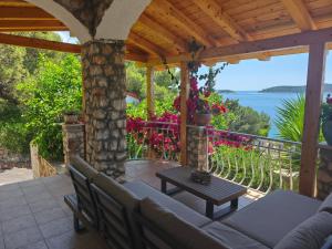 a patio with a couch and a table and flowers at Blue Paradise Apartman 2 in Sevid