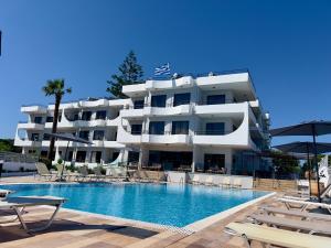 a large white hotel with a swimming pool and chairs at Ivory Serenity in Theologos