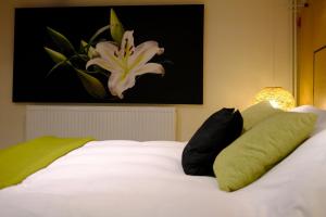 a white bed with black pillows and a painting on the wall at Eryri Golden Stays in Capel Garmon