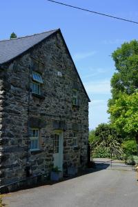 an old stone house with a white door at Eryri Golden Stays in Capel Garmon