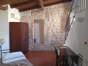 a bedroom with a bed and a table and a stone wall at Hotel Corte Altavilla in Conversano +93 photos