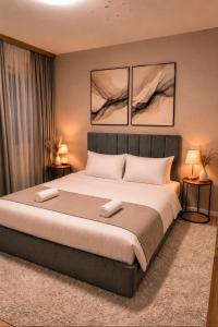 a bedroom with a large bed with three paintings on the wall at AS Apartment Tetovo in Tetovo