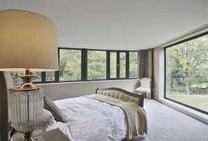 a bedroom with a bed with a lamp and windows at 6 Bed in Lavenham oc-stofa in Lavenham