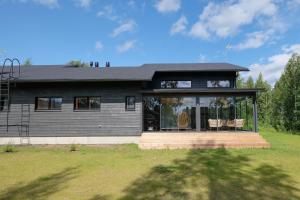 a black house with two chairs in front of it at Villa Arvonpiha A in Tahkovuori