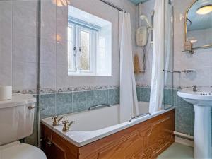 a bathroom with a tub and a sink at Ruffles Cottage Dunster in Dunster +25 photos