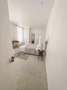a white bedroom with a bed and a table at La Maison Cannoise in Cannes