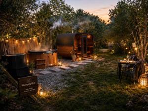 a cabin with a hot tub and a table with lights at Glamping Hive in Čmeliny