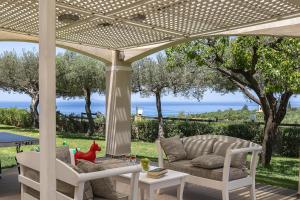 a patio with a couch and chairs under a pergola at Carme Villas in Adelianos Kampos