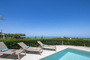 a swimming pool with two lounge chairs next to a swimming pool at Carme Villas in Adelianos Kampos