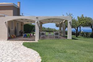 a pavilion with a table and chairs on a lawn at Carme Villas in Adelianos Kampos