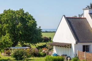 a white cottage with a tree and a field at Entre mer et rivière in Moëlan-sur-Mer