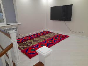 a living room with a television and a rug on the floor at Guest House Maral in Bokonbayevo
