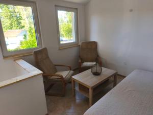 a room with two chairs and a table and two windows at Sárga311 Üdülőház Szeged in Szeged