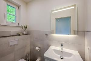 a white bathroom with a sink and a mirror at Traumgarten Haus Leichte Brise in Prerow +25 photos