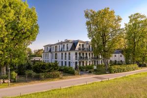 a large white building on a street with trees at Strandhaus Zingst Apartment 11 in Zingst