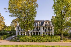 a large white house with trees in front of it at Strandhaus Zingst Apartment 16 in Zingst