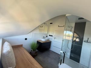 an attic bathroom with a sink and a shower at Ferienhaus Sarcander in Glowe +32 photos