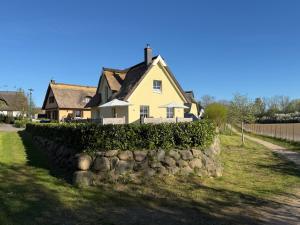 a yellow house behind a stone wall at Ferienhaus Sarcander in Glowe