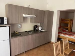 a kitchen with wooden cabinets and a bed in a room at Panoráma Szálláshely in Csongrád