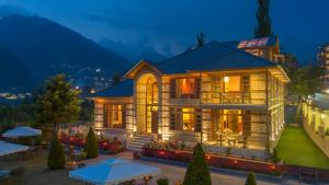 a large wooden house with tables and umbrellas at Padma Villa - Mountain Estate in Manali in Manāli