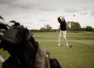 a woman swinging a golf club on a golf course at Matfen Hall Hotel and Golf - Outstanding New Spa Opening September 15th in Matfen