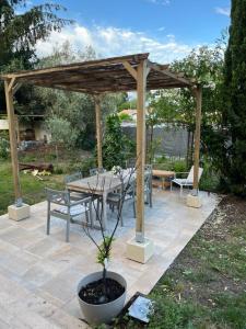 a wooden pergola with a table and chairs on a patio at L Entre Deux chambres d hôtes in Belin-Beliet