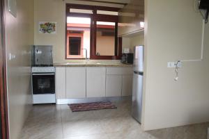 a kitchen with white cabinets and a sink and a refrigerator at Moorea Lodge Arii in Afareaitu +2 photos