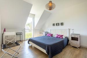 a bedroom with a bed with pink pillows and a chair at Entre mer et rivière in Moëlan-sur-Mer