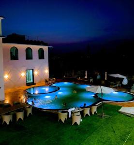 a large swimming pool at night with chairs around it at Shiv Resort & Palace in Shivpurī