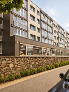 a building with a stone wall next to a street at Nemunas in Panevėžys
