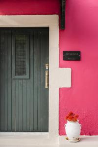 a pink building with a green door and a potted plant at Art House Near to Saint George Beach by Konnect in Págoi