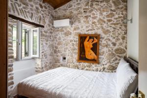 a bedroom with a stone wall with a bed at Art House Near to Saint George Beach by Konnect in Págoi +10 photos
