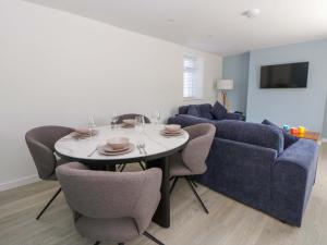 a living room with a table and a blue couch at Rosemary Cottage 1 in Tywyn