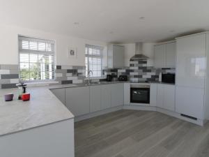 a large kitchen with white cabinets and a stove at Rosemary Cottage 1 in Tywyn