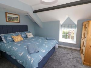 a bedroom with a bed with blue walls and a window at Rosemary Cottage 1 in Tywyn