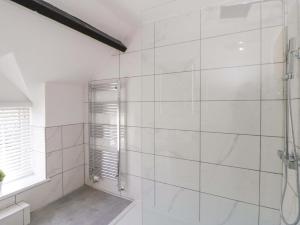 a white tiled bathroom with a shower and a window at Rosemary Cottage 1 in Tywyn +29 photos
