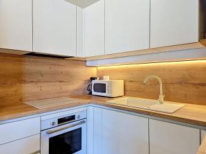 a kitchen with white cabinets and a sink and a microwave at Holiday Home Peter by Interhome in Prigradica