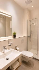 a bathroom with a toilet and a sink and a shower at Hotel Artrium am Park in Dietzenbach +39 photos