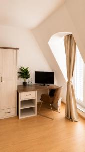 a room with a desk with a computer and a window at Hotel Artrium am Park in Dietzenbach