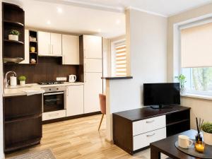 a kitchen with white cabinets and a table with a television at Nemunas in Panevėžys