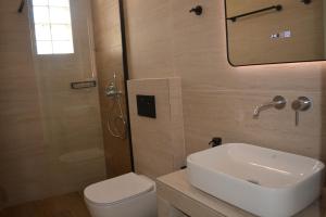 ein Badezimmer mit Waschbecken, Toilette und Spiegel in der Unterkunft Klados Studios & Apartments in Cherronisos