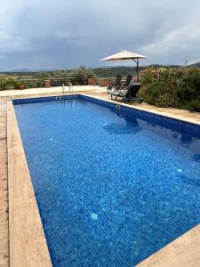 a blue swimming pool with an umbrella and a chair at Kindya Stone House in Kemikler