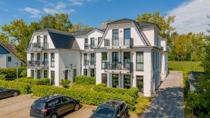 a large white house with two cars parked in front at Strandhaus Zingst Apartment 14 in Zingst
