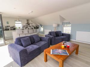 a living room with two blue couches and a coffee table at Rosemary Cottage 2 in Tywyn