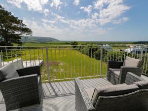 a balcony with chairs and a fence with a view of a field at Rosemary Cottage 2 in Tywyn